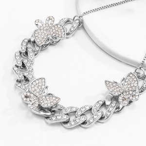 Close-up of silver Cuban anklet featuring three oversized butterfly pendants with rhinestones
