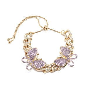 Macro detail of gold Cuban link anklet featuring sparkling purple butterfly charms