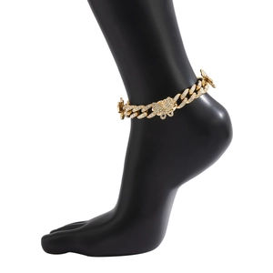 Detail view of gold Cuban link anklet with pavé butterfly charms on a black foot model