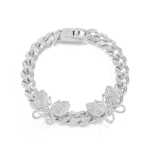 Macro shot of silver Cuban link anklet with iced-out butterfly charms and pavé diamonds