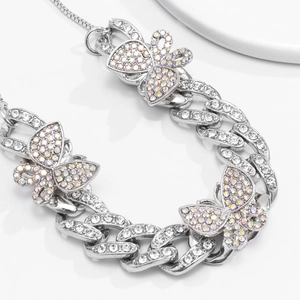 Macro shot of silver Cuban link anklet featuring sparkling rhinestones and iridescent butterflies