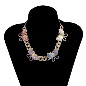 Macro detail of gold Cuban link chain necklace with large colorful rhinestone butterflies