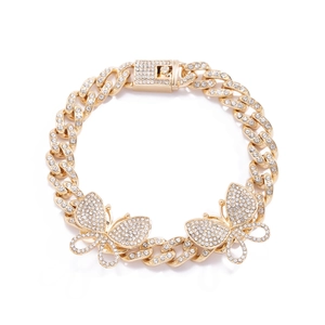 Macro detail of gold Cuban link anklet featuring luxury iced-out butterfly and rhinestones