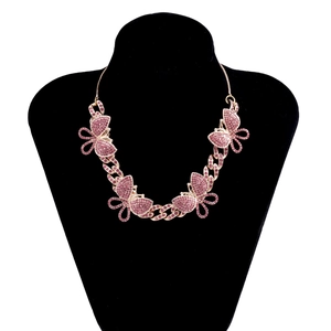 Close-up of pink crystal butterfly charms on a rose gold Cuban chain necklace