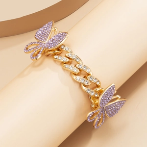 Close-up of golden Cuban chain anklet with purple rhinestone butterfly and detailed pavé
