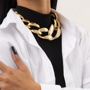 Close-up of a chunky gold punk chain necklace worn over a black turtleneck sweater