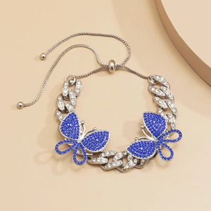 Close-up of adjustable silver Cuban chain anklet with blue rhinestone butterflies