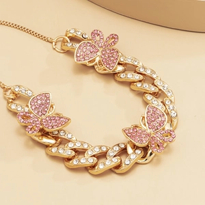 Macro view of gold Cuban link anklet with pink rhinestone butterfly charms and crystals