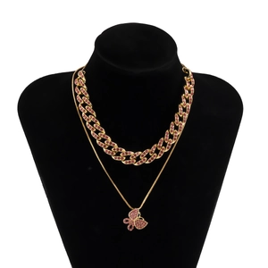 Detail einer doppelten Goldkette mit rosa Strass-Schmetterling auf schwarzer Büste