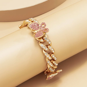 Detailed close-up of golden Cuban link anklet with pink rhinestone butterfly accent