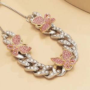 Close-up of a silver Cuban link anklet featuring sparkling pink rhinestone butterflies
