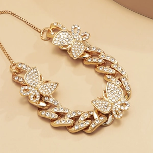 Close-up of gold Cuban link anklet with shimmering butterfly charms and iced-out crystals