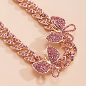 Detail of rose gold Cuban link necklace with iced out pink butterfly and rhinestones