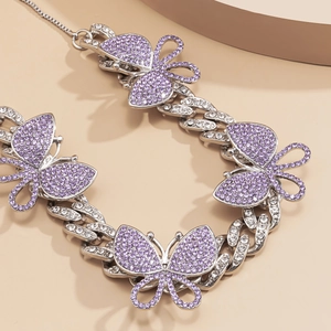 Macro detail of silver Cuban chain with purple rhinestone butterflies and sparkling crystals