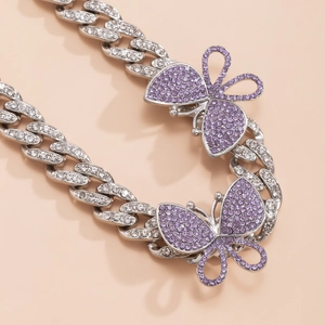 Macro shot of silver Cuban link chain with purple rhinestone butterflies and white gems