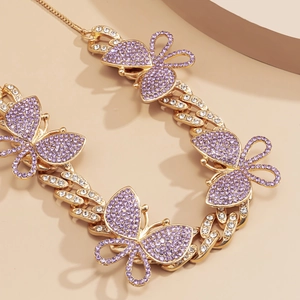 Macro shot of gold Cuban chain necklace with purple rhinestone butterfly charms