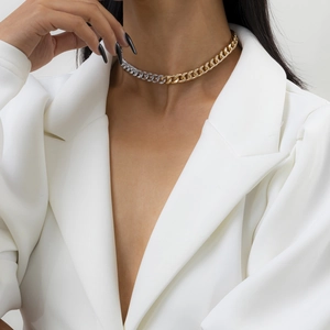 Close-up of mixed gold and silver Cuban link chain necklace worn with a white blazer