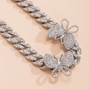 Detailed view of silver Cuban chain anklet featuring iced-out butterfly pendants with crystals