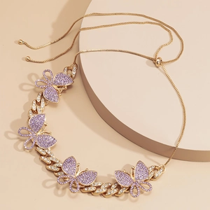 Macro detail of gold Cuban link chain necklace with purple butterfly charms and crystal inlay