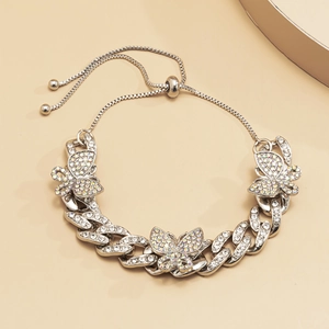 Detail of silver Cuban chain anklet with sparkling rhinestone butterfly pendants and crystal