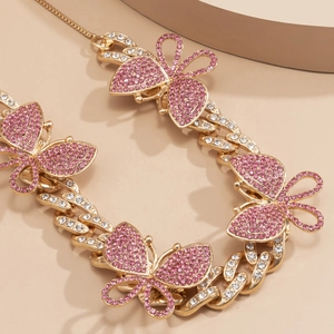 Detailed view of gold Cuban chain necklace with pink rhinestone butterflies and lobster clasp