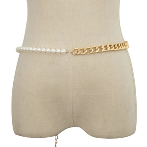 Detail of elegant waist chain with white pearls and gold-tone curb chain on a beige mannequin