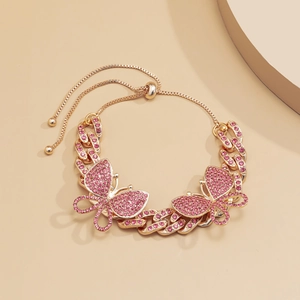 Detail of gold Cuban link anklet featuring a pink rhinestone butterfly and bolo clasp