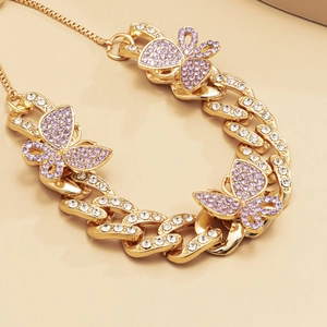 Detail of gold Cuban chain anklet with purple and white crystal butterfly charms