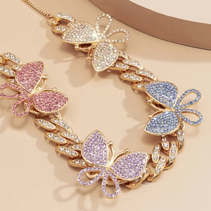 Close-up of golden Cuban chain necklace featuring colorful rhinestone butterfly charms