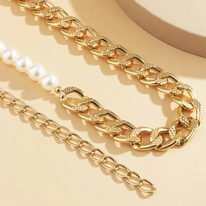 Close-up of golden geometric chain with white pearls and vintage diamond-textured links