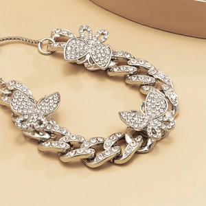 Macro view of silver butterfly anklet featuring iced-out Cuban links and crystals