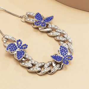 Detail of silver Cuban link anklet with blue rhinestone butterflies and diamond accents