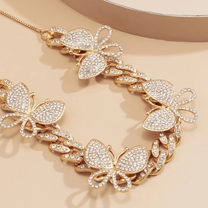 Detail of gold Cuban chain necklace with four crystal-encrusted butterflies in macro view