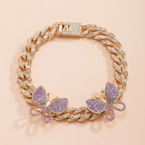 Macro shot of gold Cuban link bracelet with purple crystal butterfly charms and rhinestones