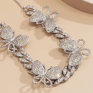 Macro detail of silver Cuban chain necklace featuring colorful AB rhinestone butterfly pendants