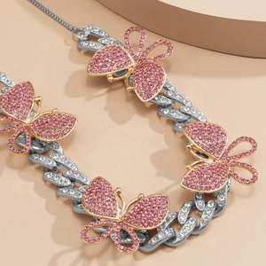 Close-up of hip hop cuban chain featuring gold butterflies and pink rhinestones