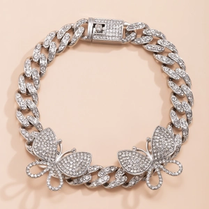 Close-up of silver Cuban link anklet featuring oversized pavé butterfly charms and rhinestones