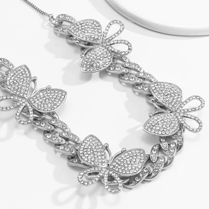 Macro detail of silver Cuban link necklace featuring iced-out butterfly charms and diamonds
