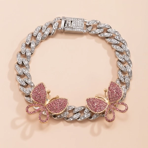 Close-up of iced-out Cuban link anklet featuring sparkling pink butterfly pendants