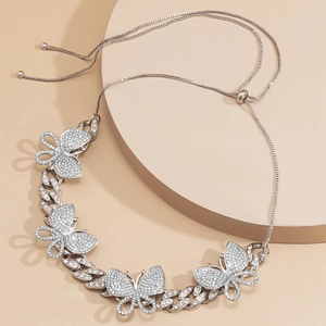 Detail of silver Cuban chain necklace with sparkling colorful butterfly pendants