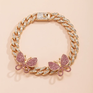 Macro detail of gold Cuban link anklet with pink rhinestone butterflies and iced-out clasp