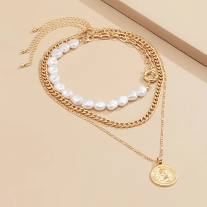 Three-layer layered necklace detail with irregular pearls, gold curb chain and coin pendant