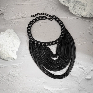 Macro view of matte black multilayer fringe chains with thick curb link detail