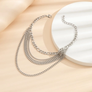Macro detail of layered silver chain necklace featuring figaro links and lobster clasp