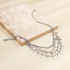 Macro view of multi-layer silver metal anklet with star charms and chunky curb chains