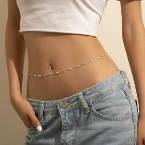 Dettaglio della catena in vita con perle vintage su modella con jeans