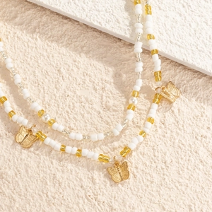 Detailed close-up of handmade beaded waist chain with gold butterfly pendants on stone