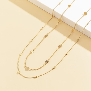 Close-up of gold double-layer body chain with geometric discs and beaded metal links