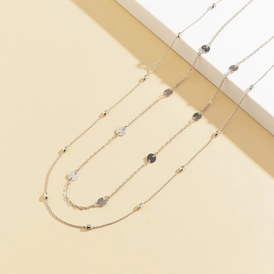 Detailed close-up of double-layered geometric silver discs and metallic chains on white podium