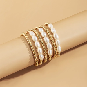Close-up of 5-piece gold beaded bracelet set with faux pearls on display stand